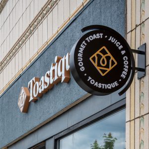 sign for Toastique in grey and gold outside of the business