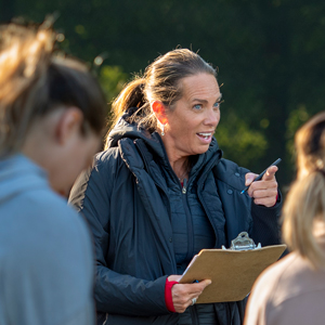 women with ponytail and clipboard talks to crowd