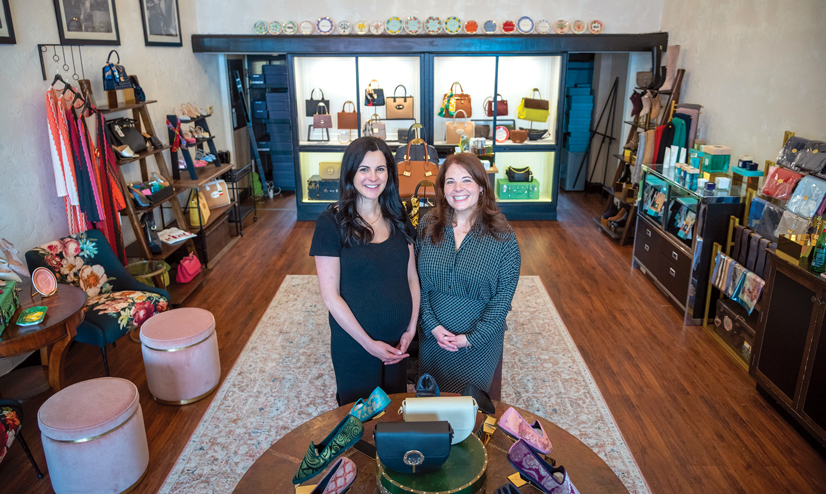 two women in dresses smile in a shoe boutique