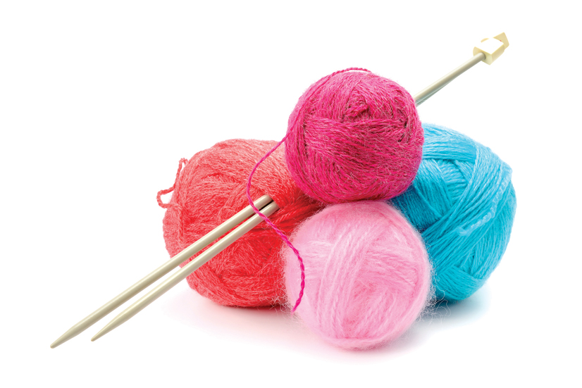 several colorful balls of yarn and knitting needles on a white background