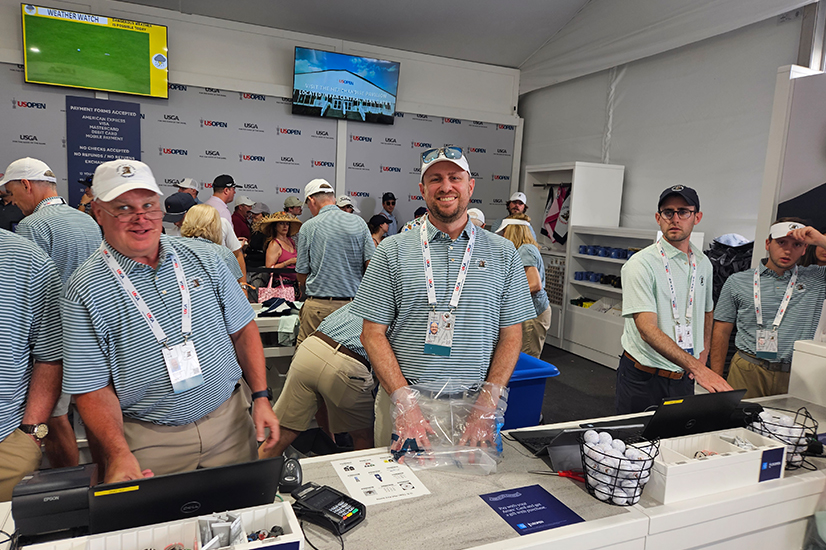 volunteers at a booth with blue and white polos and white hats at a golf event