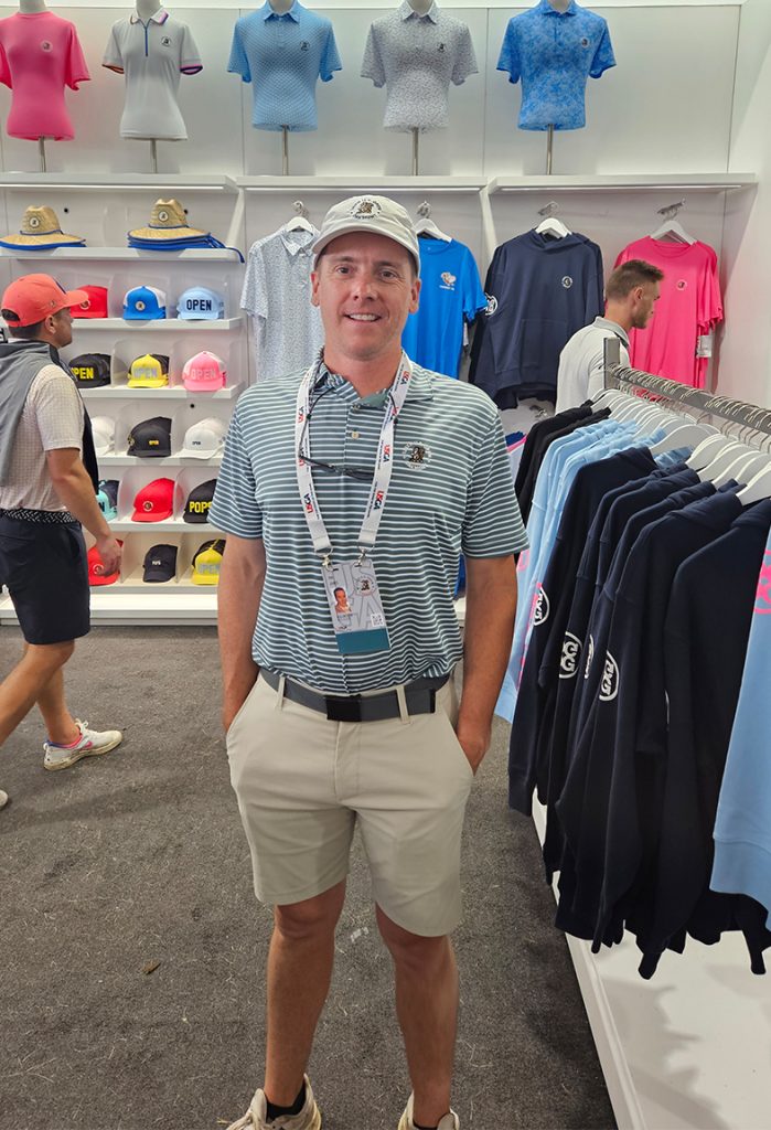 man wearing blue and white polo and khaki shorts and white hat in a store with golf clothing