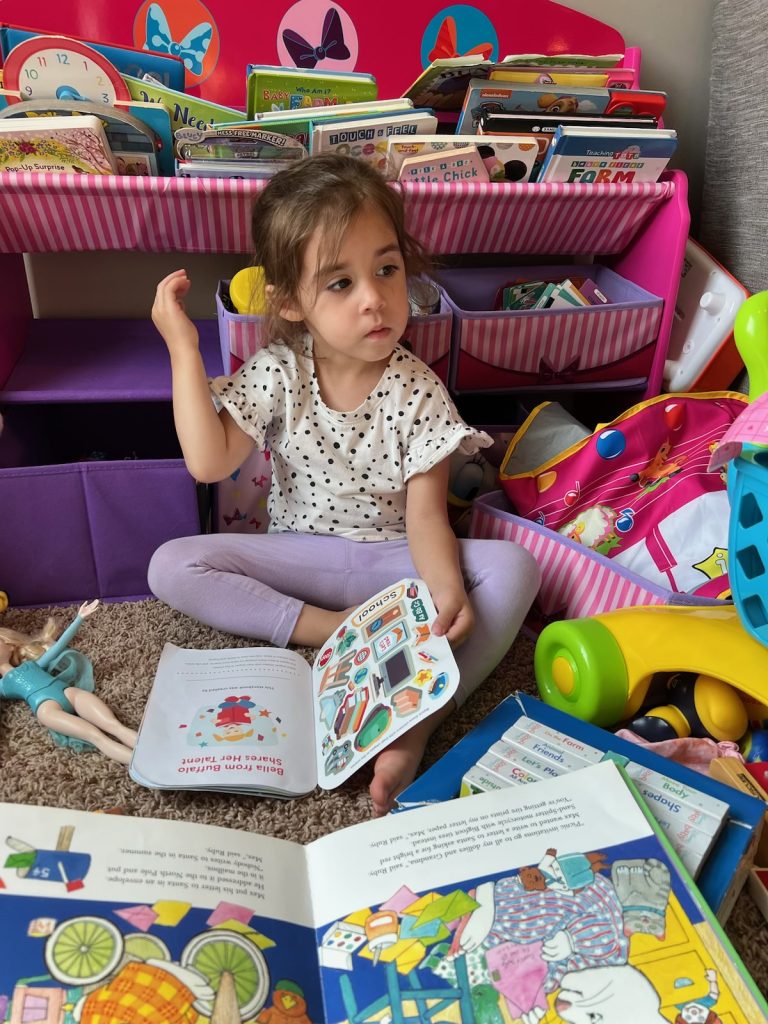 A toddler surrounded by books and toys