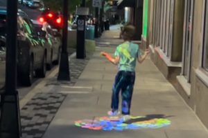 sidewalk with child walking and colorful light art projected on sidewalk