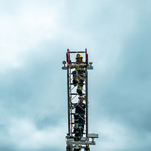 two people climbing fire ladder with cloudy sky