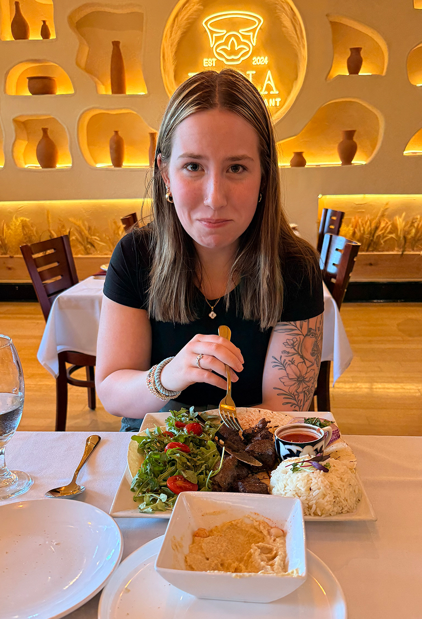 woman in black t shirt making scared face while eating in a resturant