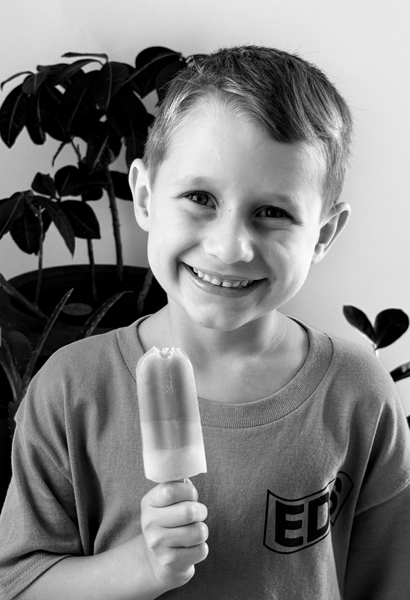 black and white photo of young boy holding popsicle 