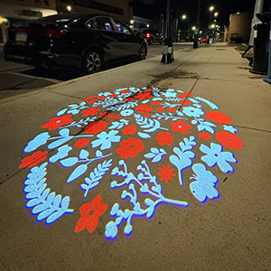 blue and red flowers projected onto sidewalk at night