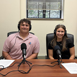 teen girl and teen boy with headphones and microphones in a conference room