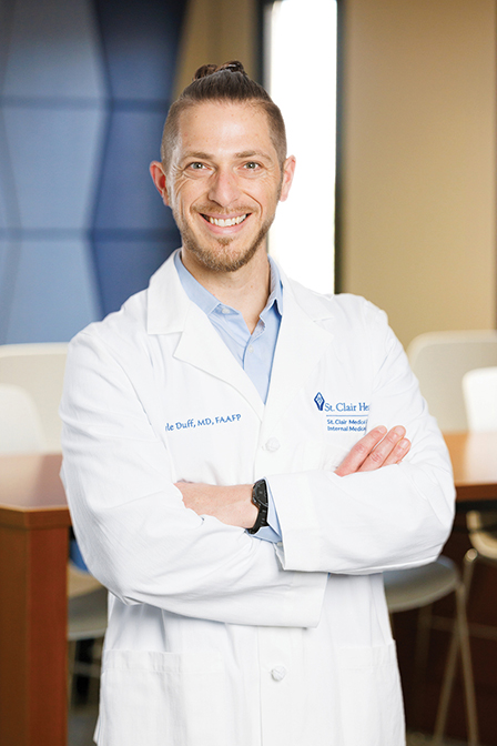A man doctor wearing a white coat crossing his arms