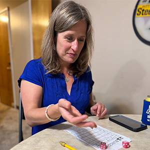 woman in blue shirt rolling dice playing bunco