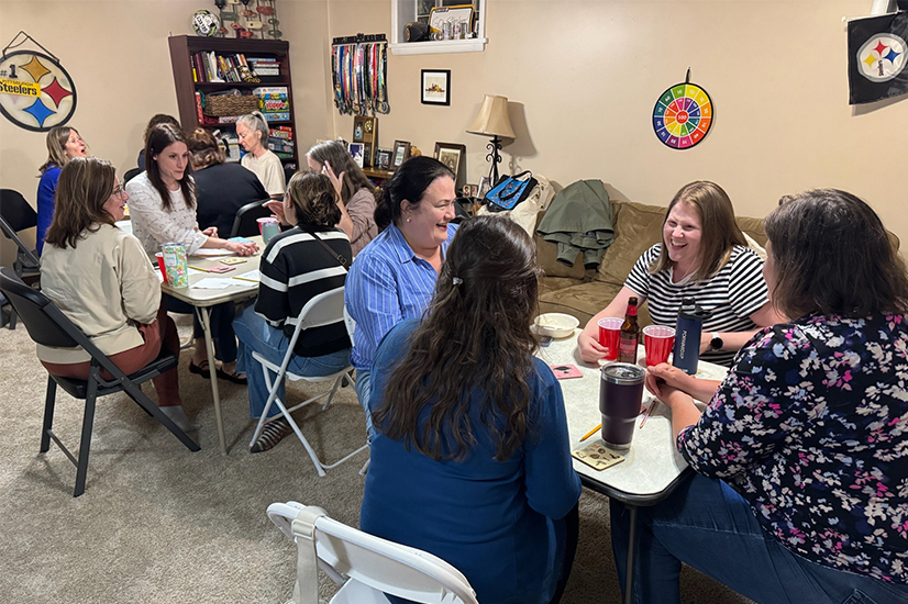 women sitting at card tables in a basement of a home