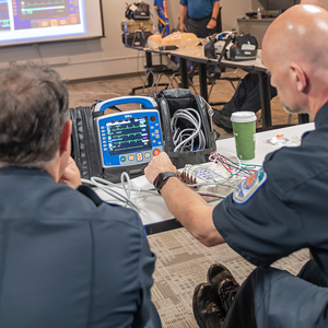 two men testing cardiac monitor on table