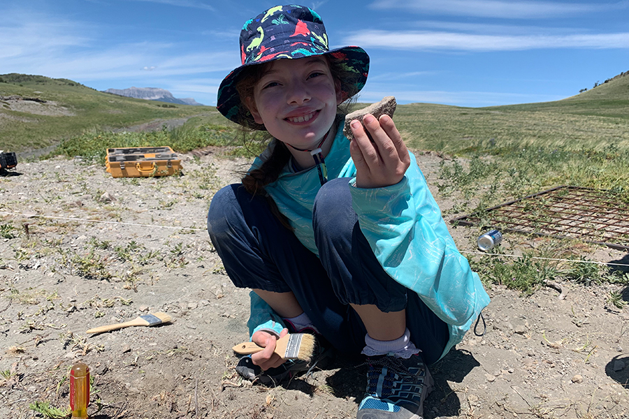 girl smiling holding a rock in an open space