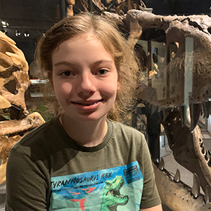 girl smiling with dinosaurs in background
