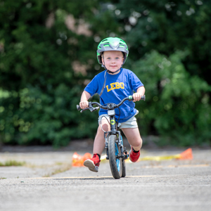 a child wearing a helmet, riding a child sized ebike