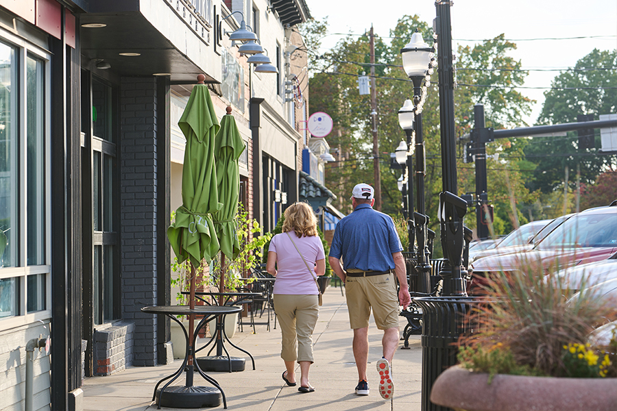 man and woman walking along business shops