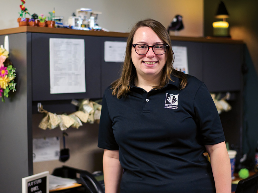 woman with long hair and black polo shirt in an office