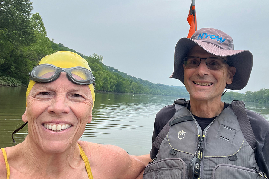 selfie of woman in swim cap and man with life jacket at a river