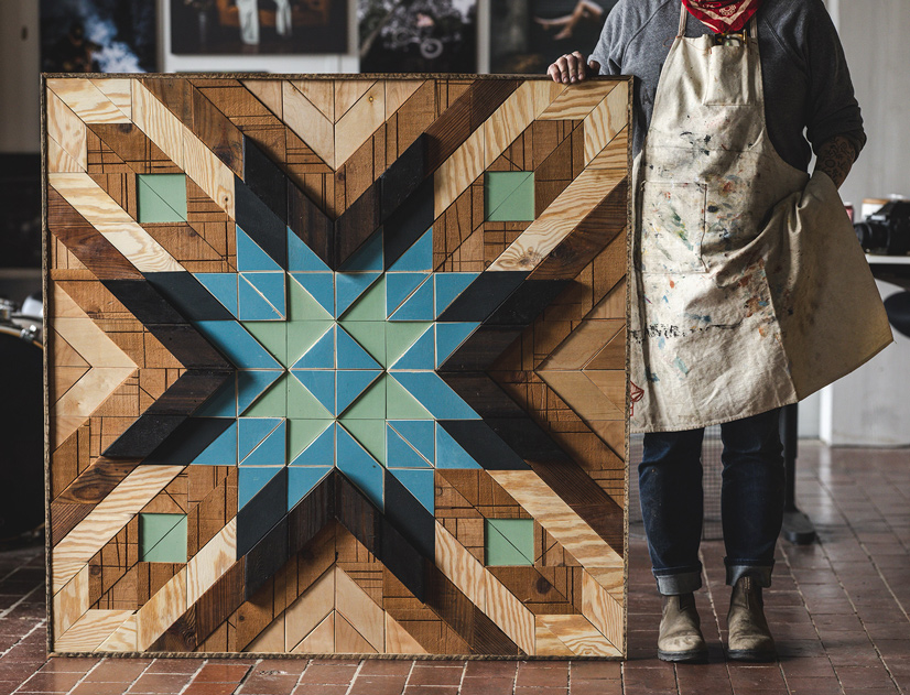 A wood sculpture that looks similar to a quilted blanket with wood grains and a turquoise blue