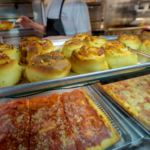 pizza and rolls in a display case