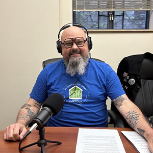 man with tattoos sitting in front of a microphone with headphones on
