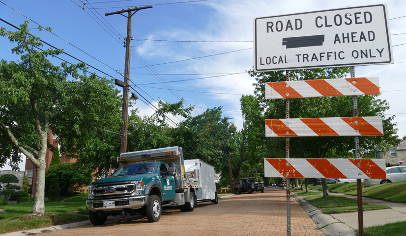 A road closed sign next to a Mt. Lebanon municipality truck parked on a brick road