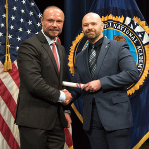 two men in suits shaking hands in front of fbi flag