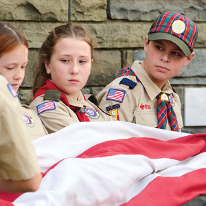 scouts holding American flag by wall