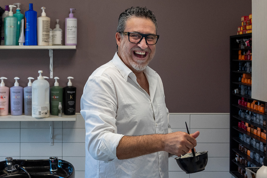 man with glasses in a hair salon smiling mixing hair product