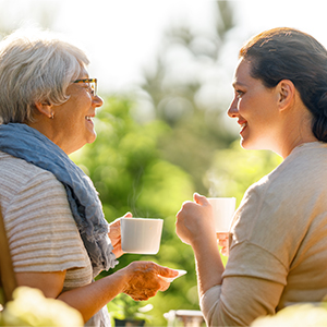 two adult women talking and holding mugs