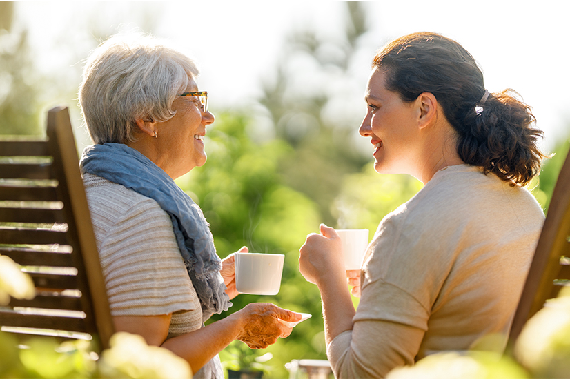 two adult women talking and holding mugs