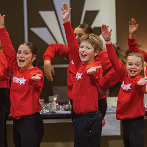 children in red shirts with arms raised smiling