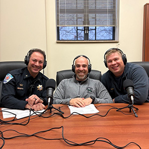 Three men with headphones on, smiling.