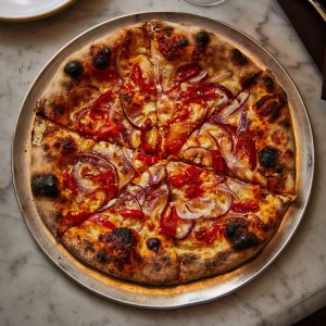 pizza with peppers and onions on a marble counter