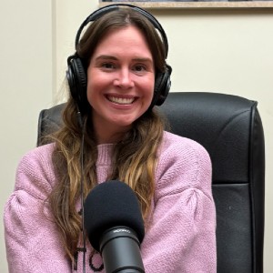 Woman with long brown hair and headphones on in front of a microphone