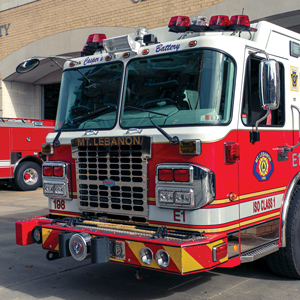 an older red and white pump fire truck parked in front of the public safety building.