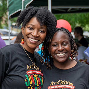 Two women both with short dark hair standing close together smiling for the camera.