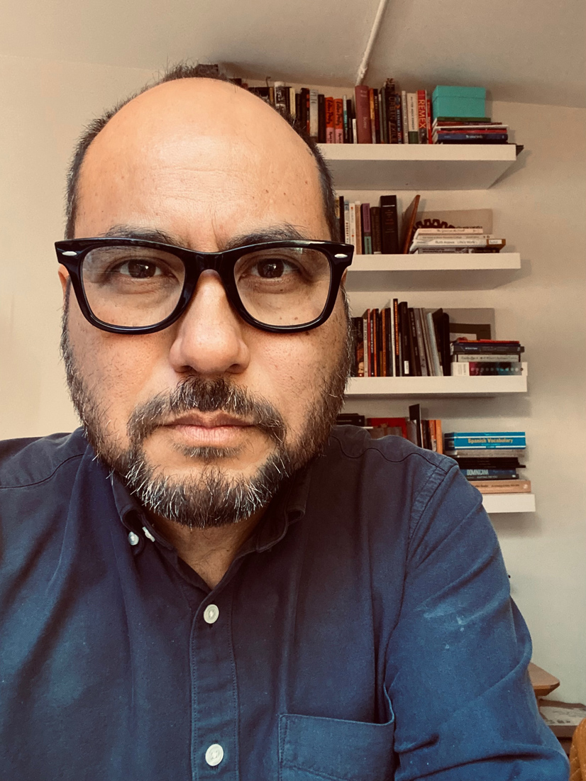 a man with a beard wearing glasses and a blue shirt.
