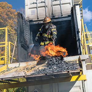 firefighter in gear extinguishing a fire at a training facility
