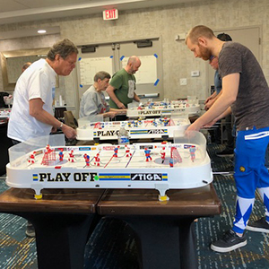 men playing table top hockey in a conference room
