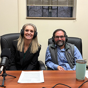 woman and man wearing headphones and sitting at a desk