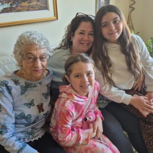 two girls and two women sit on couch smiling