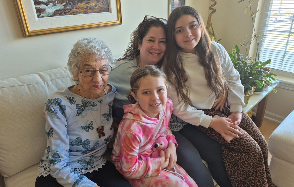 A mother and two daughters on the couch with a senior they are visiting