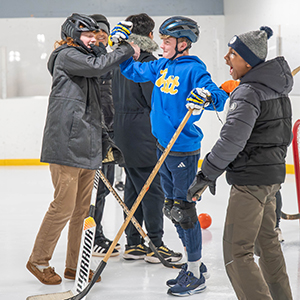 teenagers in winter clothes on an ice rink playing broomball