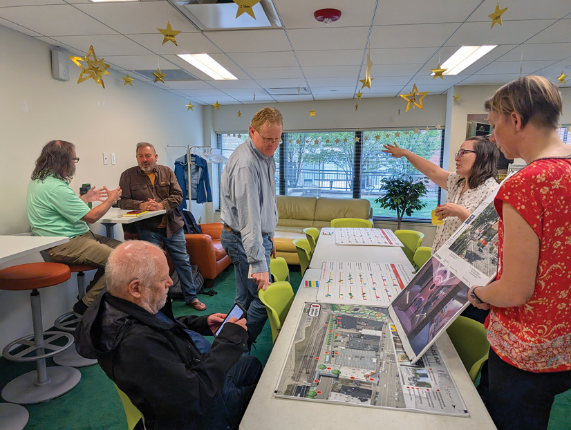 6 people in a room looking a large presentations and discussing issues