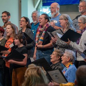 adults and one child singing in a choir holding books