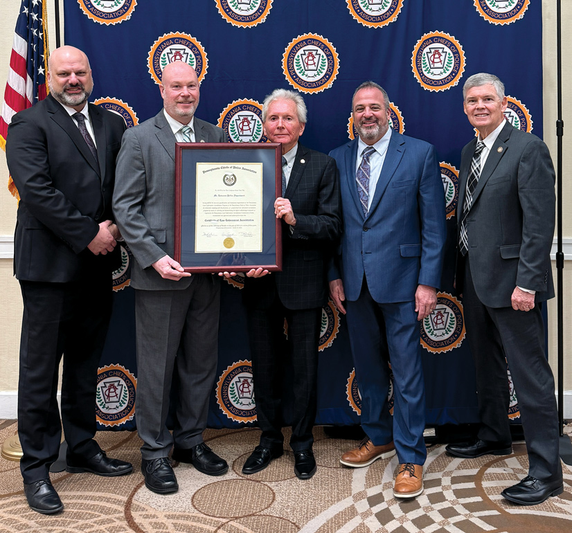 five men in suits pose for photo with a certificate