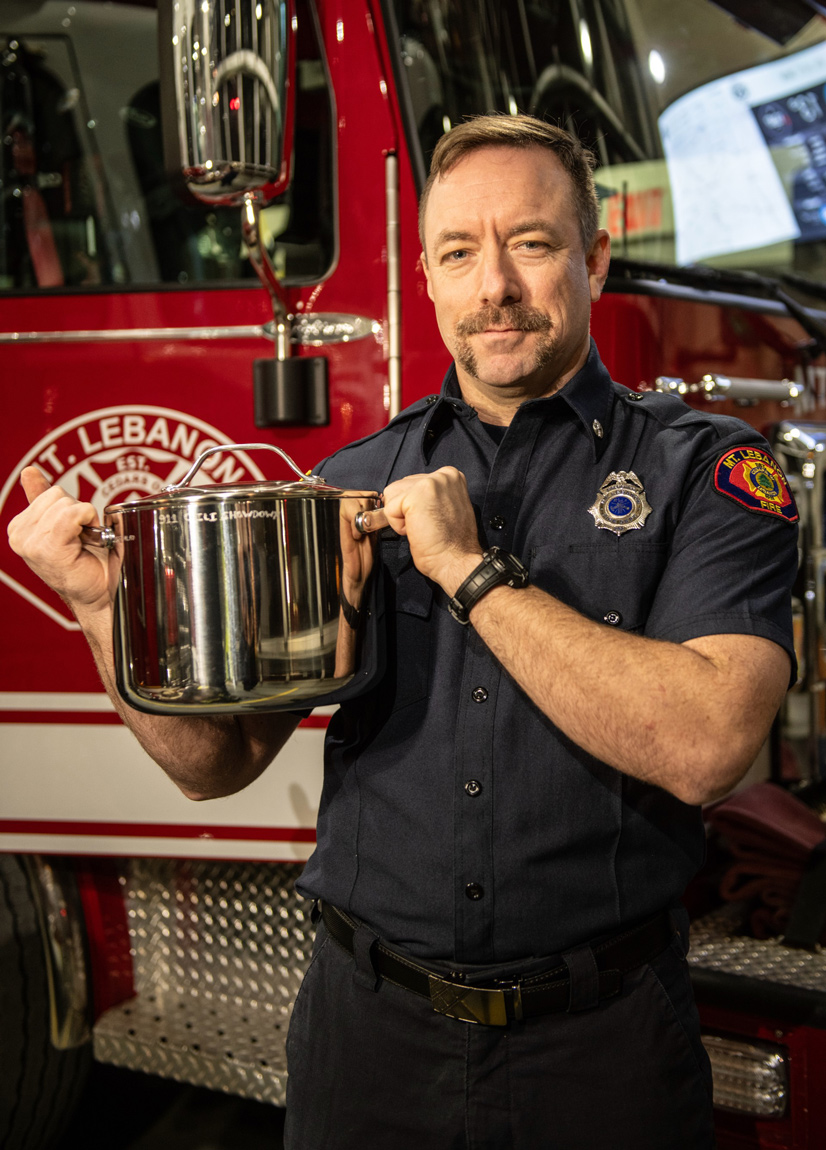 firefighter holding a chili pot in front of a fire truck
