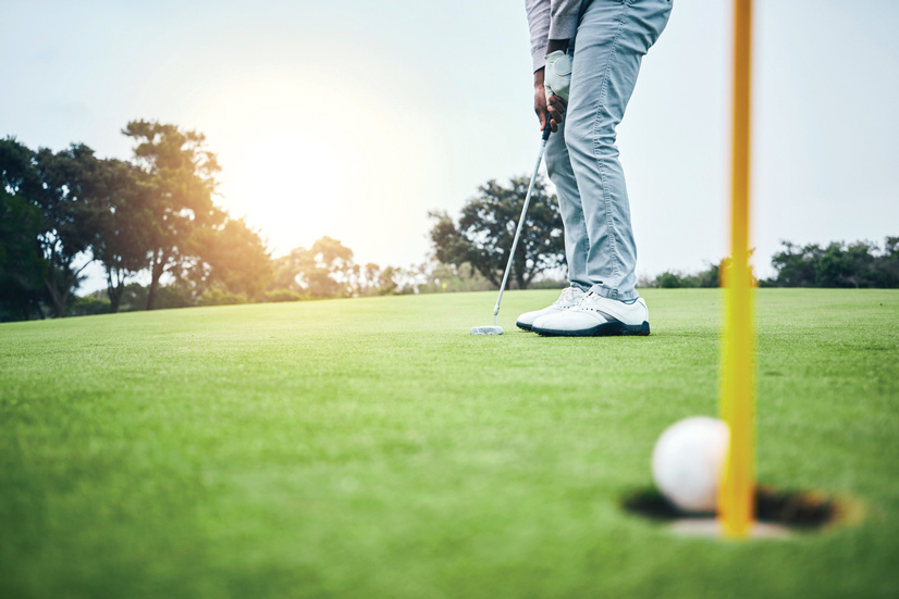 a man standing on the green putting a ball into a hole